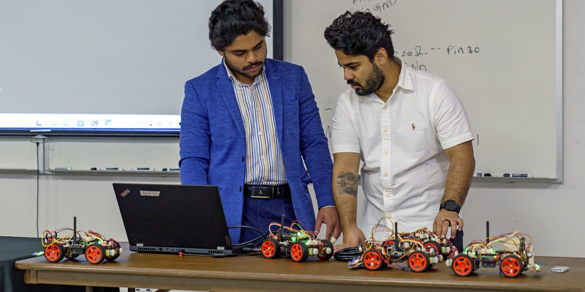 Students of Mathematics and Computer Science at a laptop computer on a table with remote cars built from kits in a classroom at UNC Pembroke.
