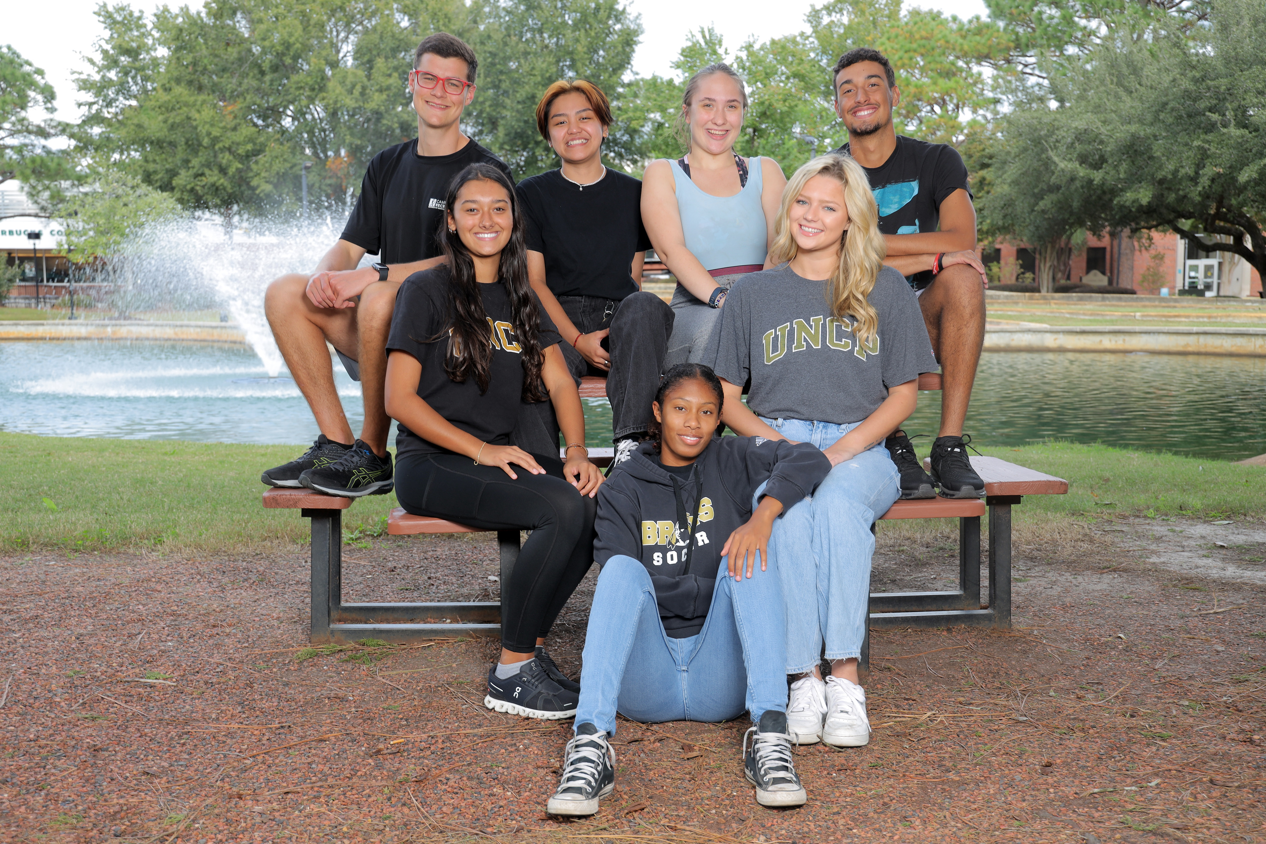 A group of diverse students in UNCP gear outside