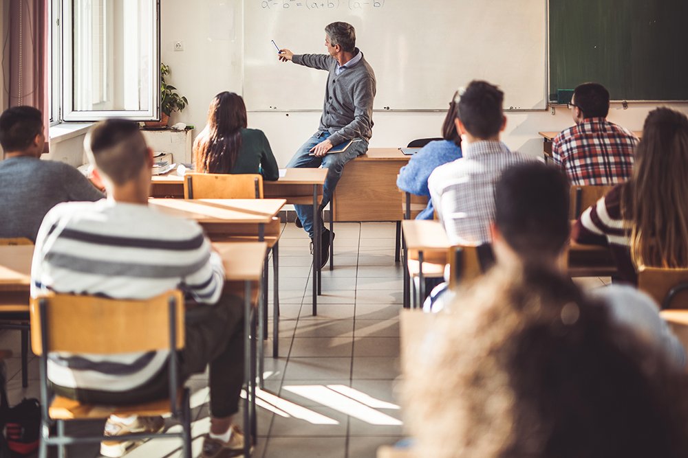 Male math teacher at the front of a classroom