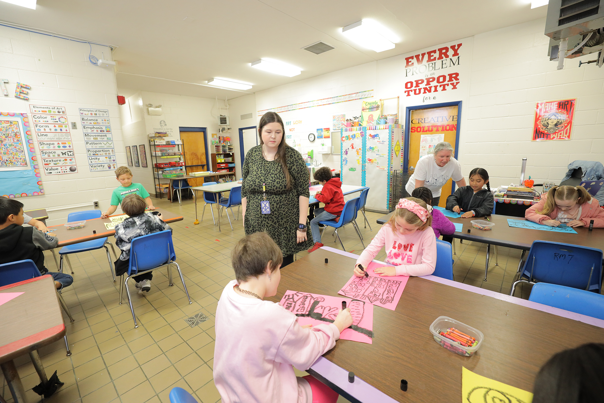 female teacher walking though an elementary school classroom