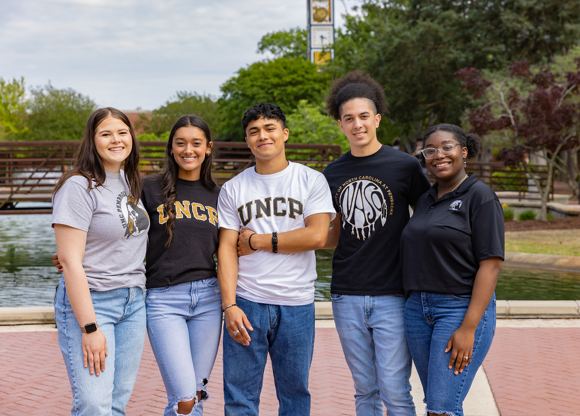 UNCP students gathered on the campus quad in front of the footbridge and water feature.