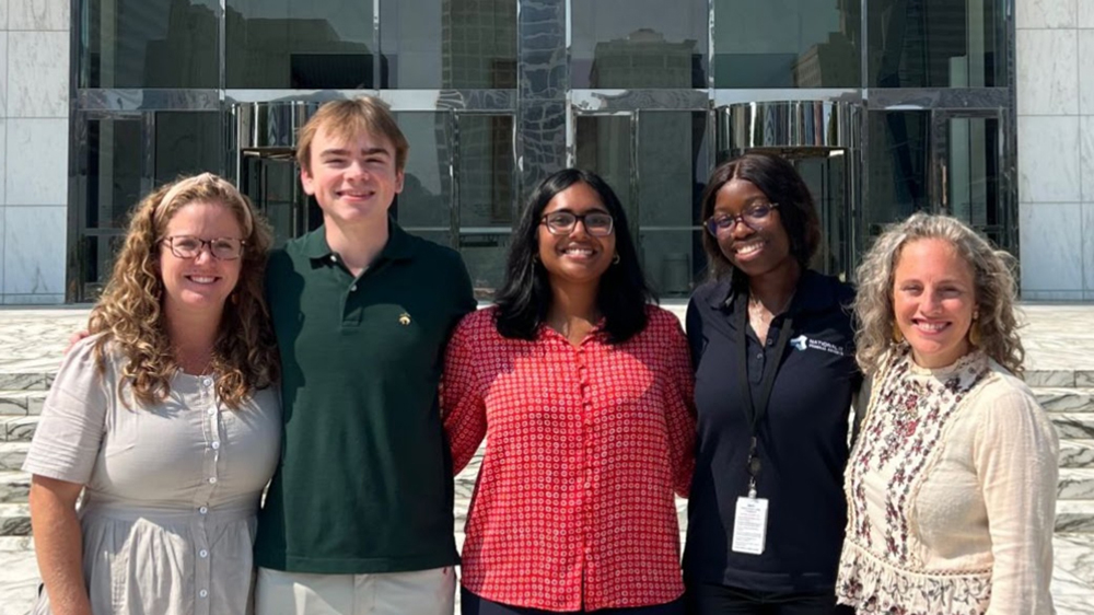Gloriest Lubamba in front of the Federal Reserve Bank of Richmond building with friends