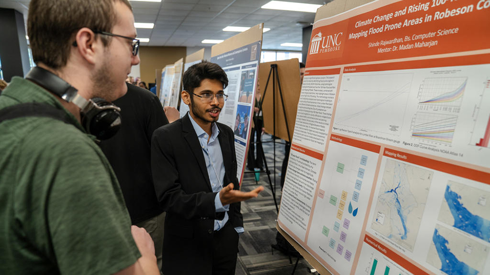 Presenter at PURC Symposium explains research poster to attendee