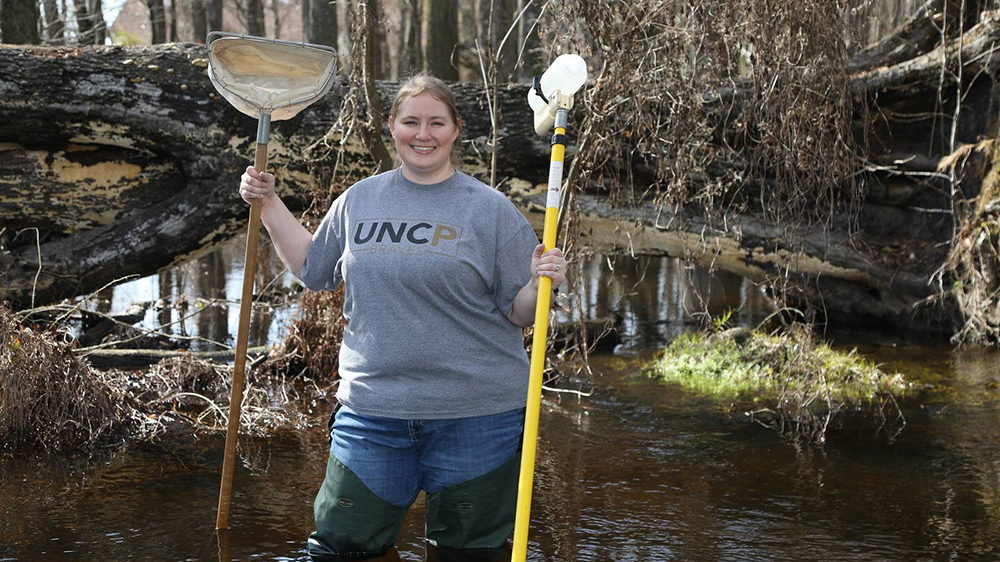 Dr. Amber Rock holding aquatics sampling gear