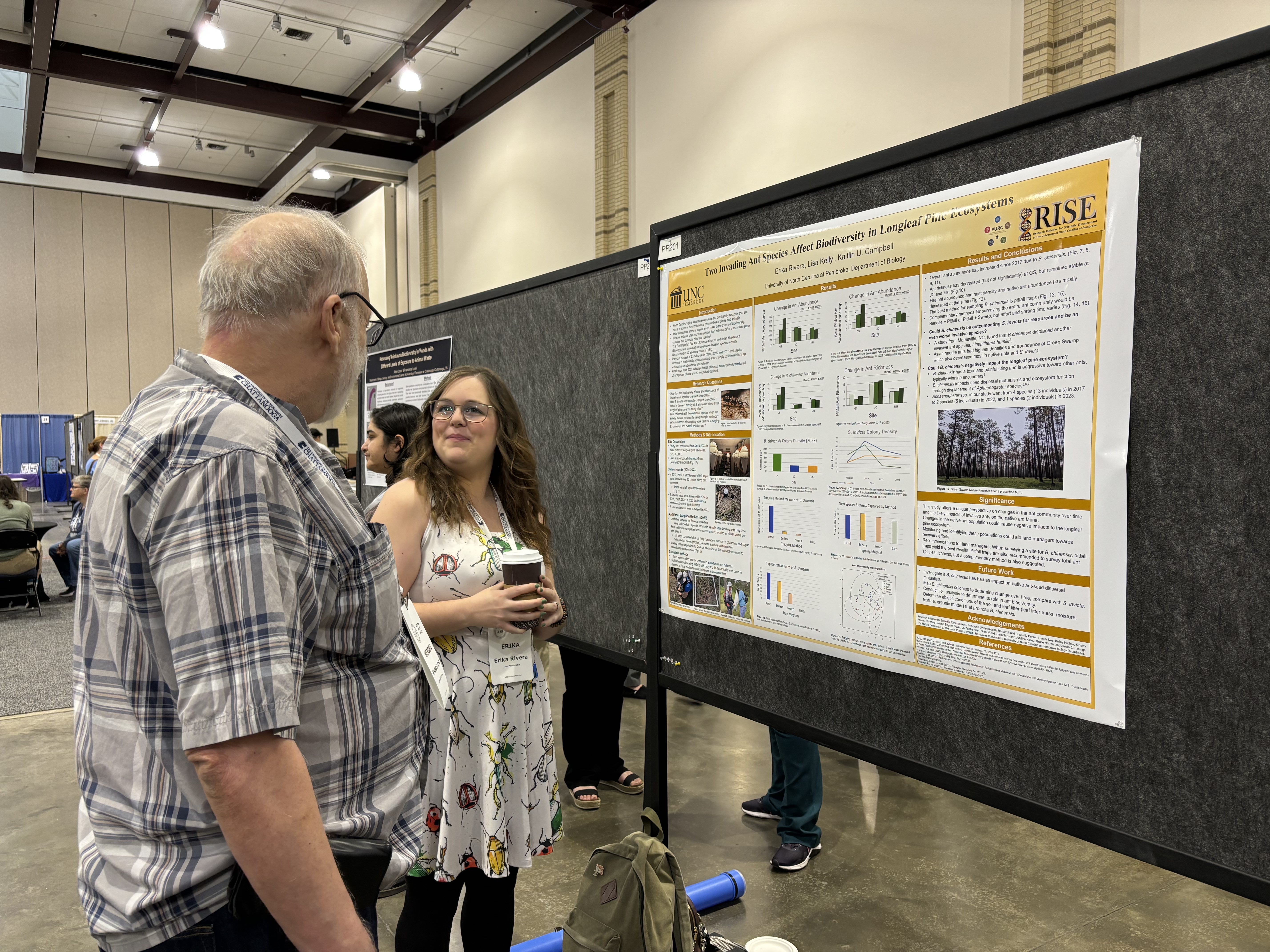Erica Rivera speaks to an attendee at the ASB Conference next to her research poster.