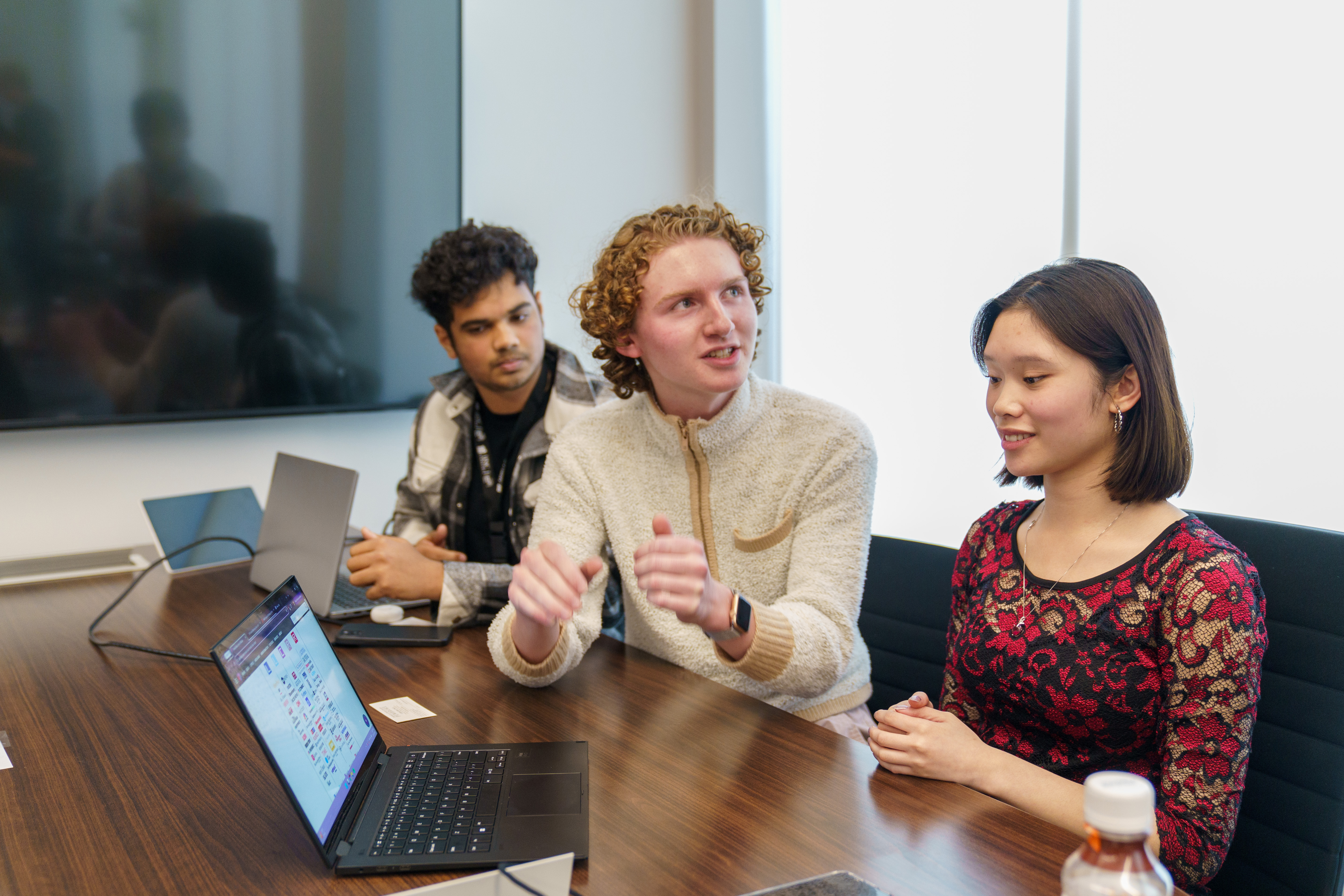 three students discussing computer work at HackUNCP