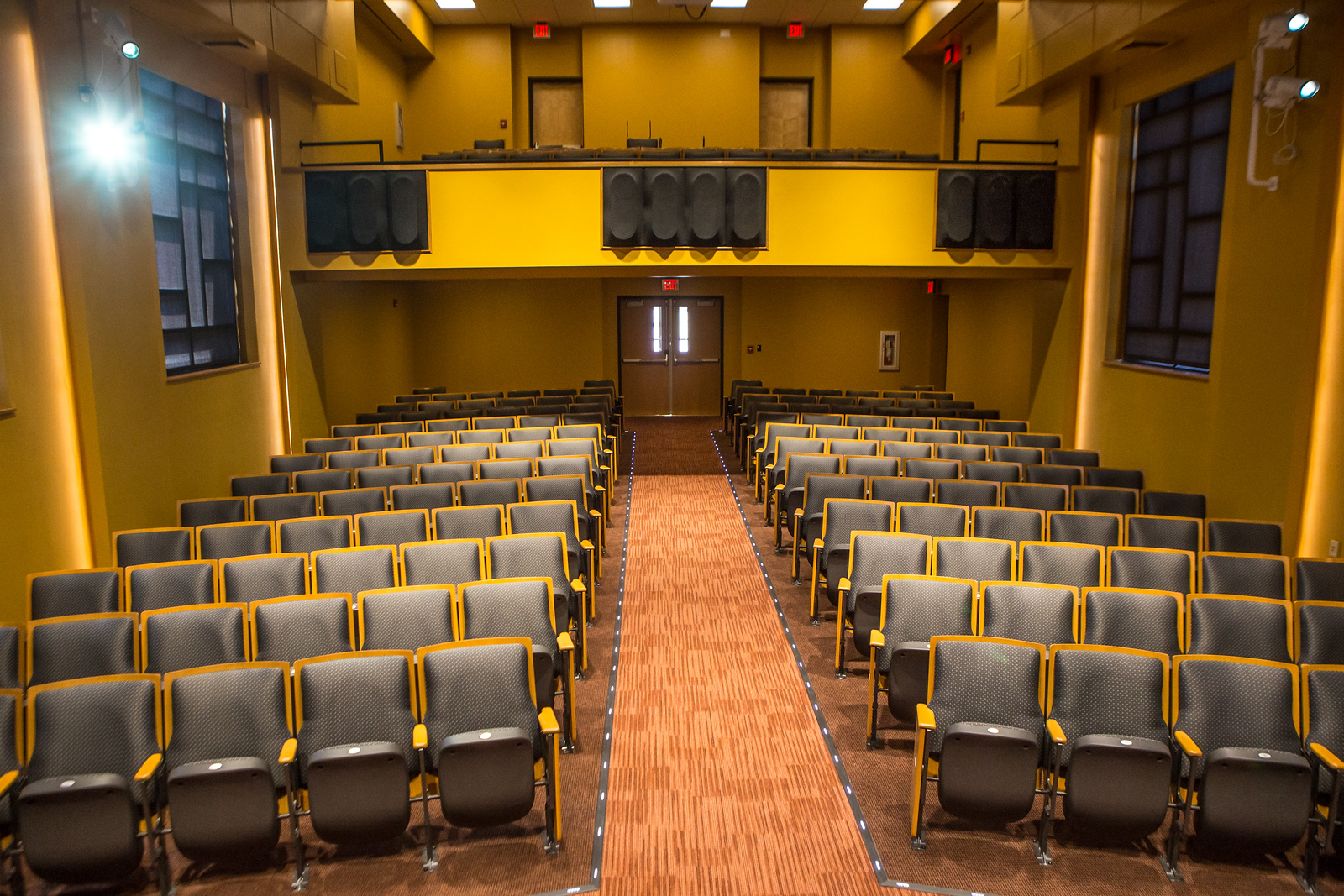 interior view of the Moore Hall Auditorium at UNC Pembroke, featuring rows of theater-style seating, a central aisle, and a balcony area, used for lectures, performances, and music education events.