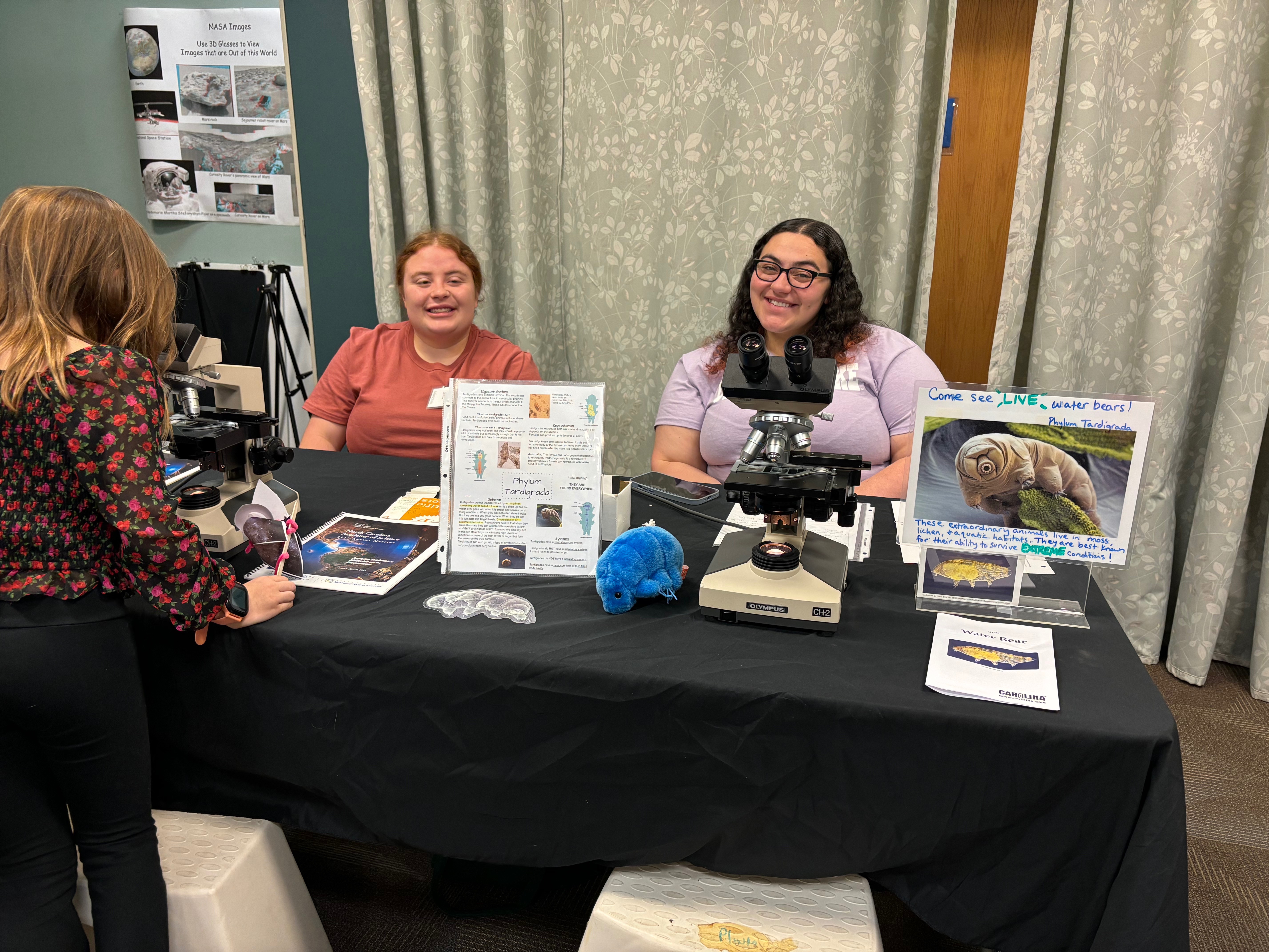 Two smiling college students set at a NCAS table at UNCP