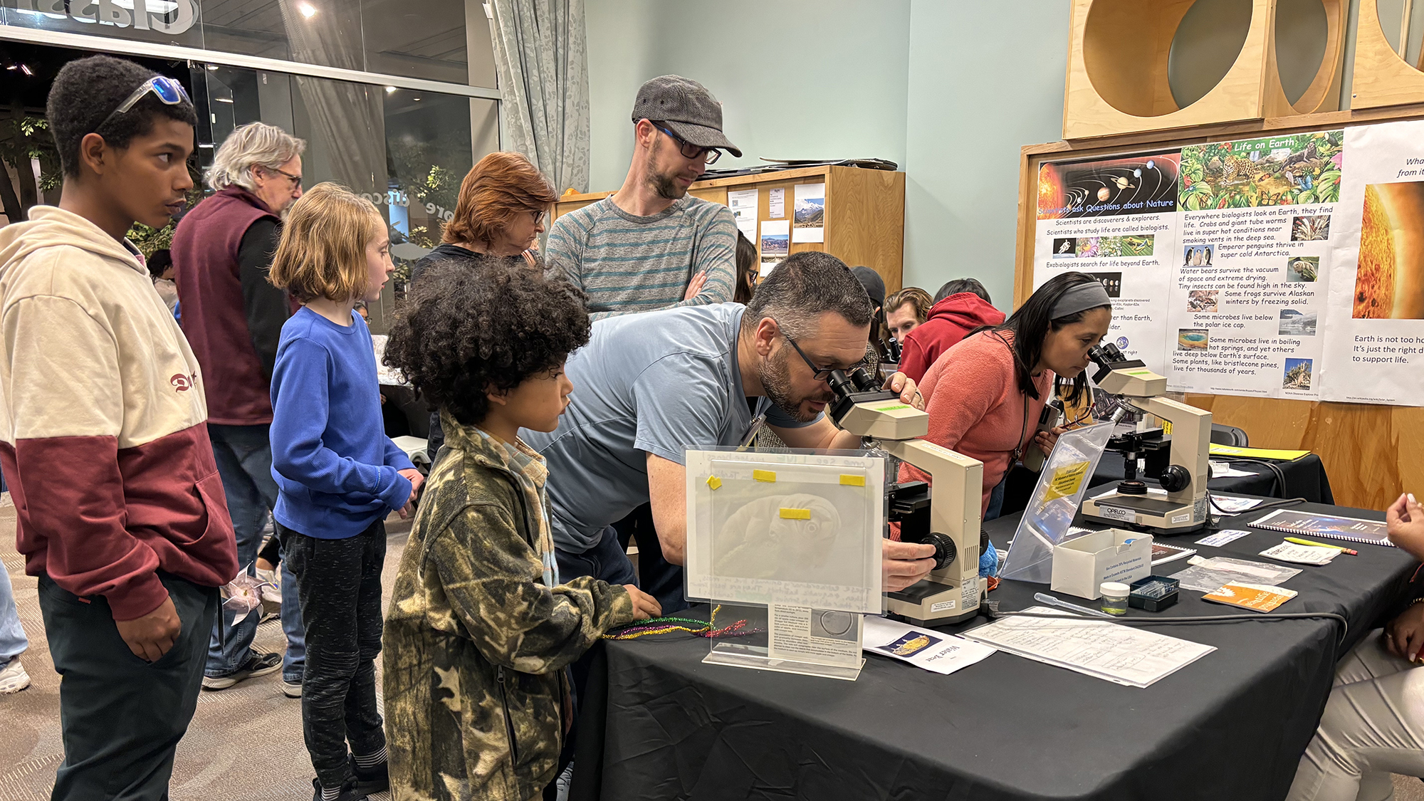 Students gather around a table to view telescopes