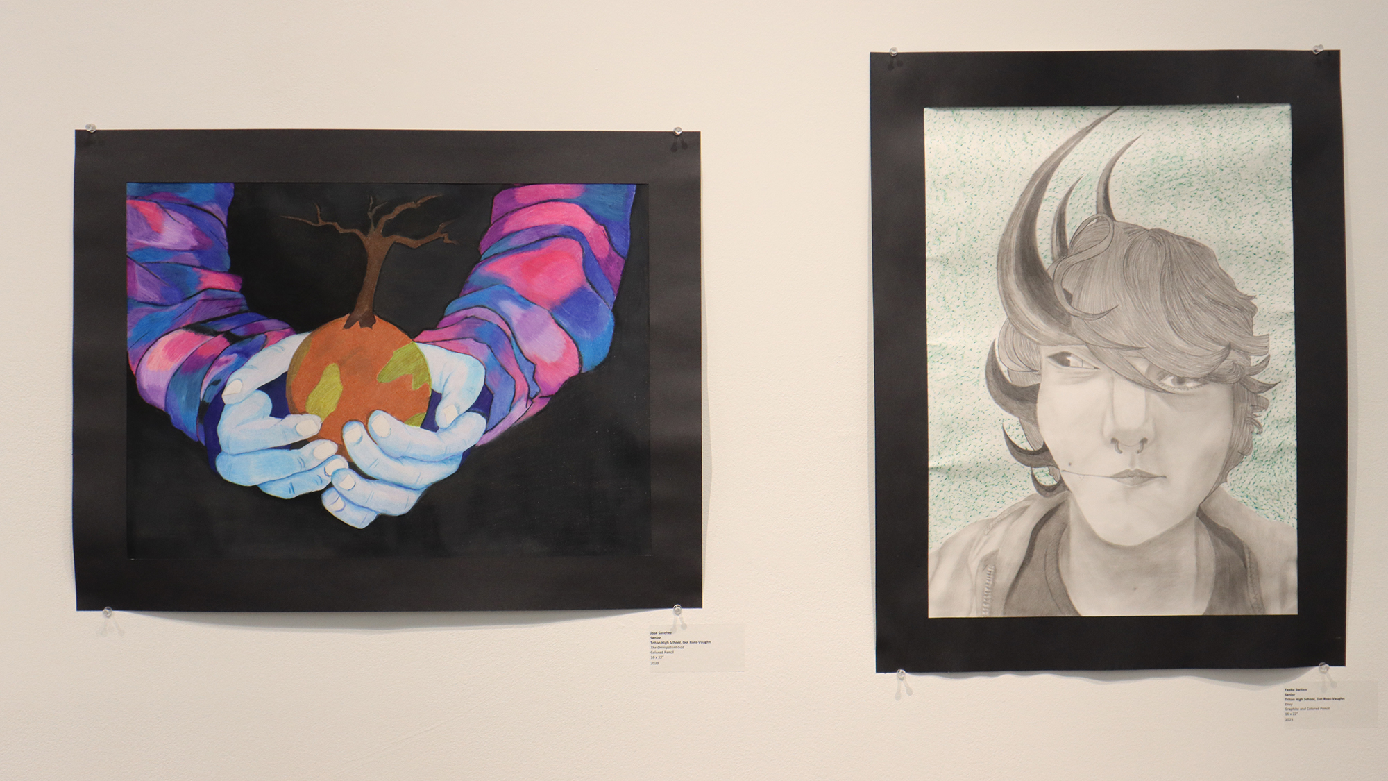 two paintings hanging on the wall. left painting of two hands holding a pear. right painting a portrait of a male with hair flying around