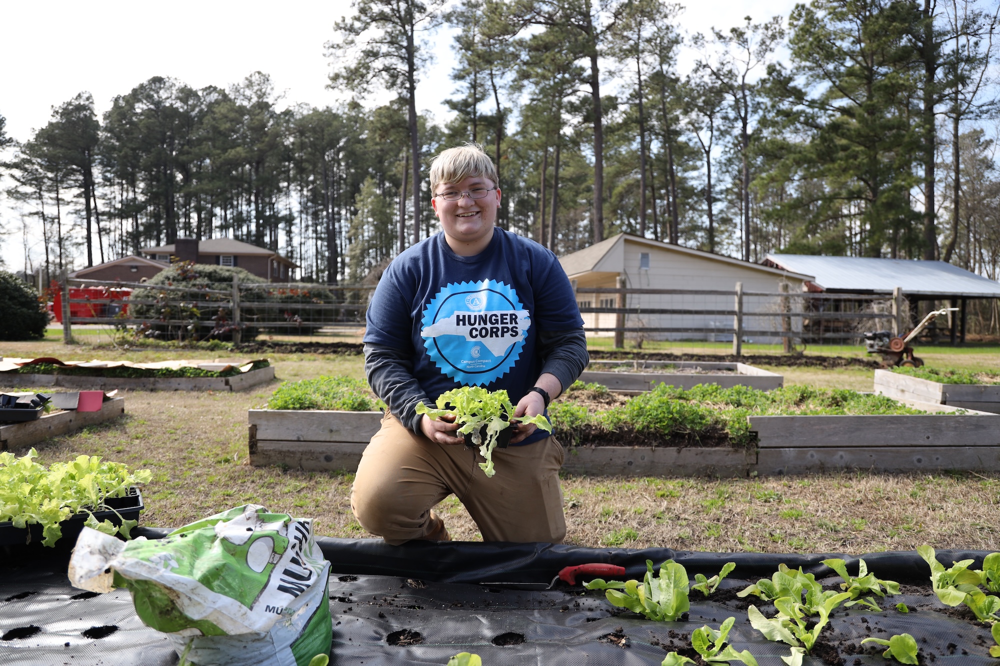 A student plants lettuce during a hands-on gardening session.