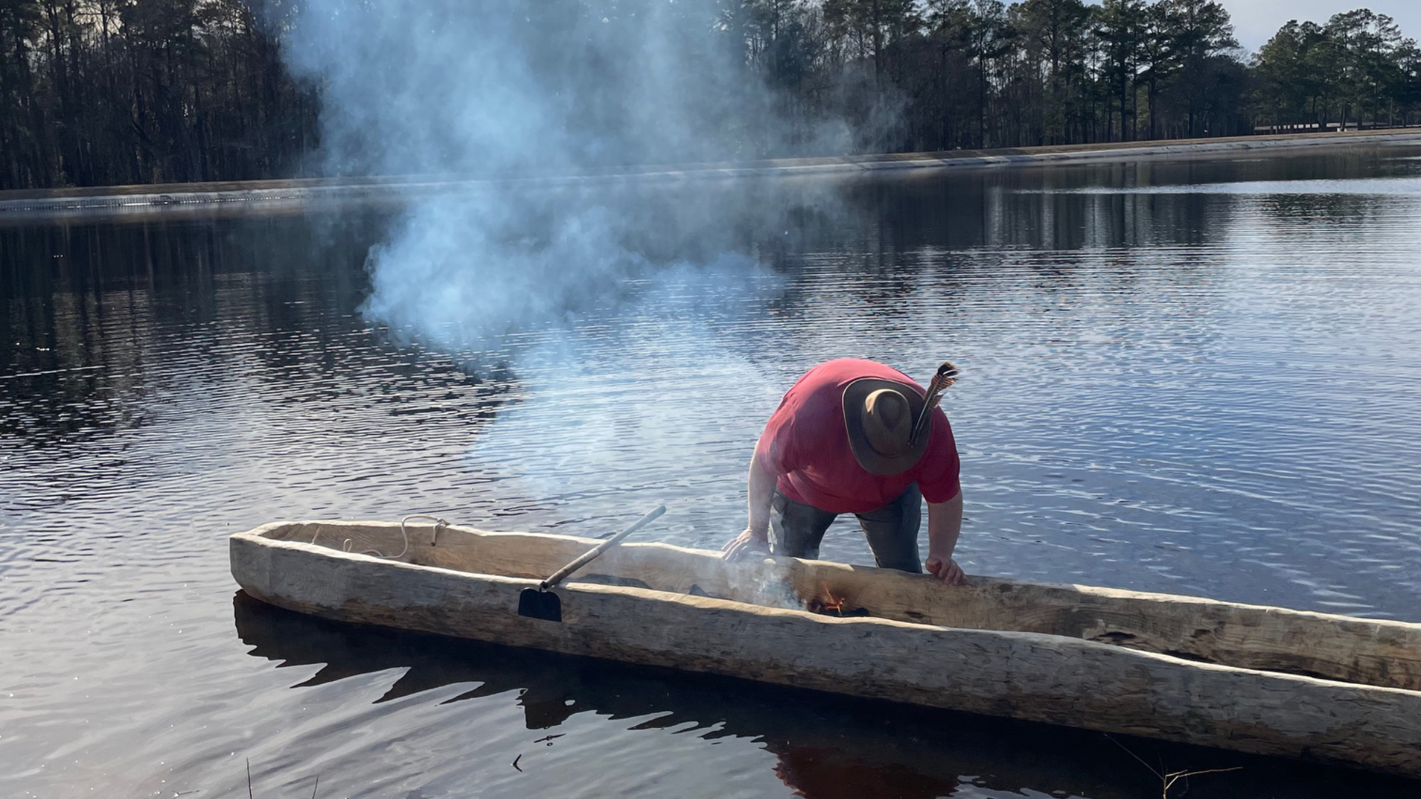 Kelvin Melvin, a Lumbee tribal member, burns the interior of the dugout canoe to shape and hollow it before water testing.
