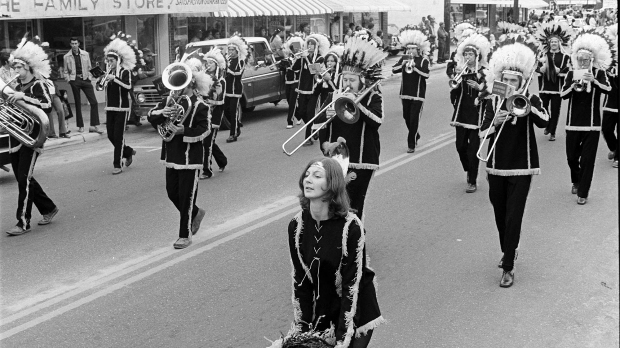marching band performs while marching down the street with female conductor at the front