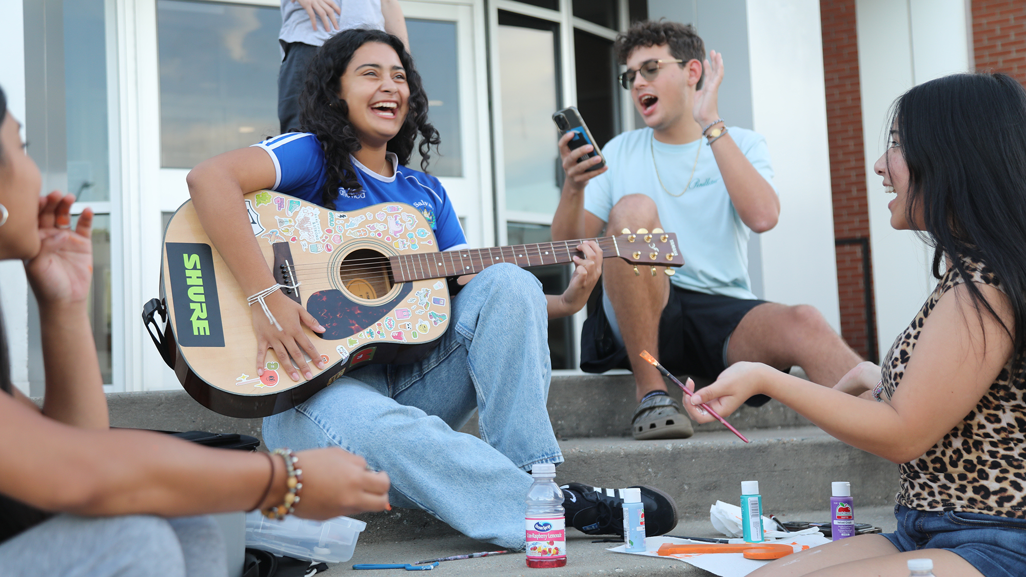 Students playing guitar on the steps outside of Oak Hall