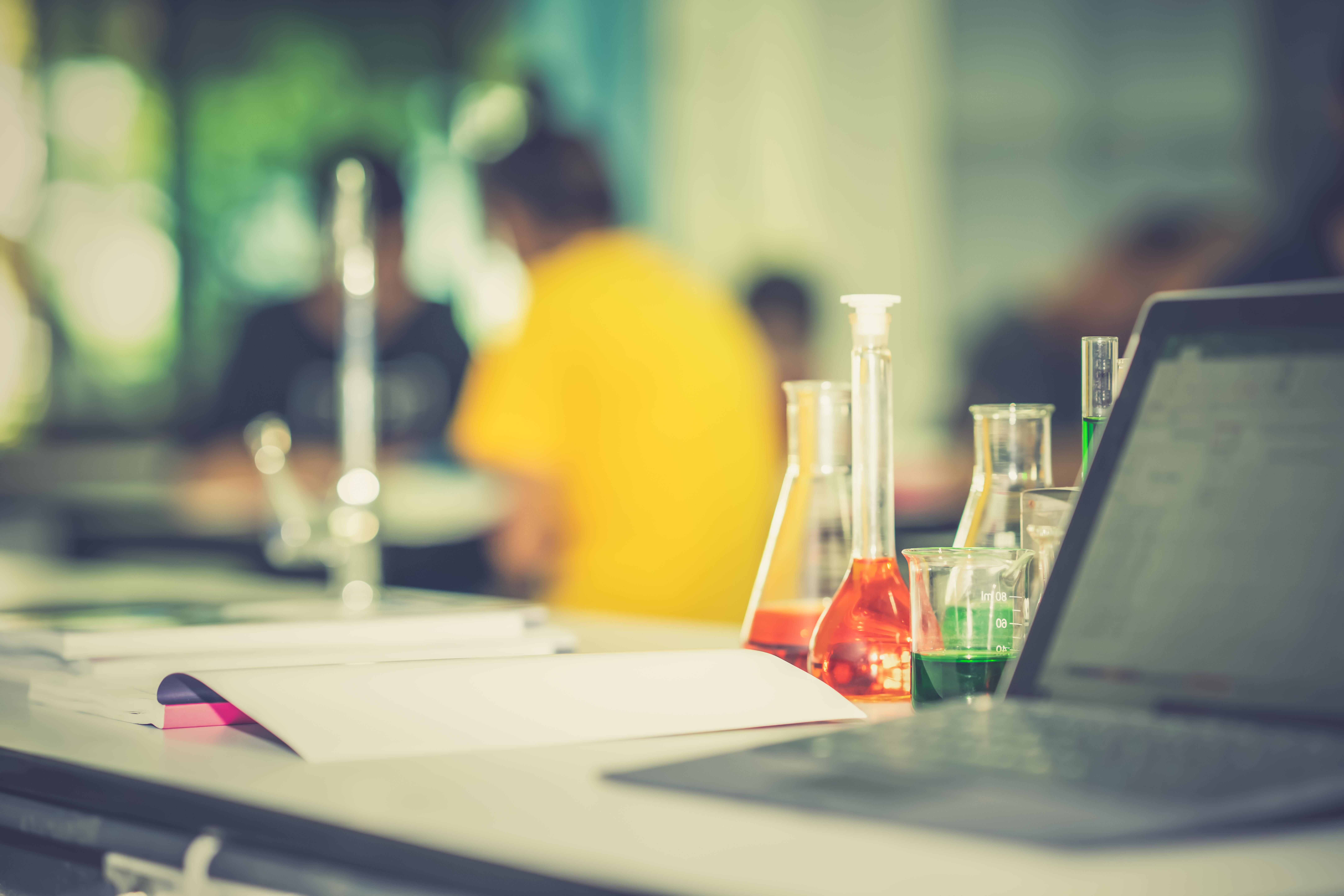 laptop, textbook and beakers in a science lab