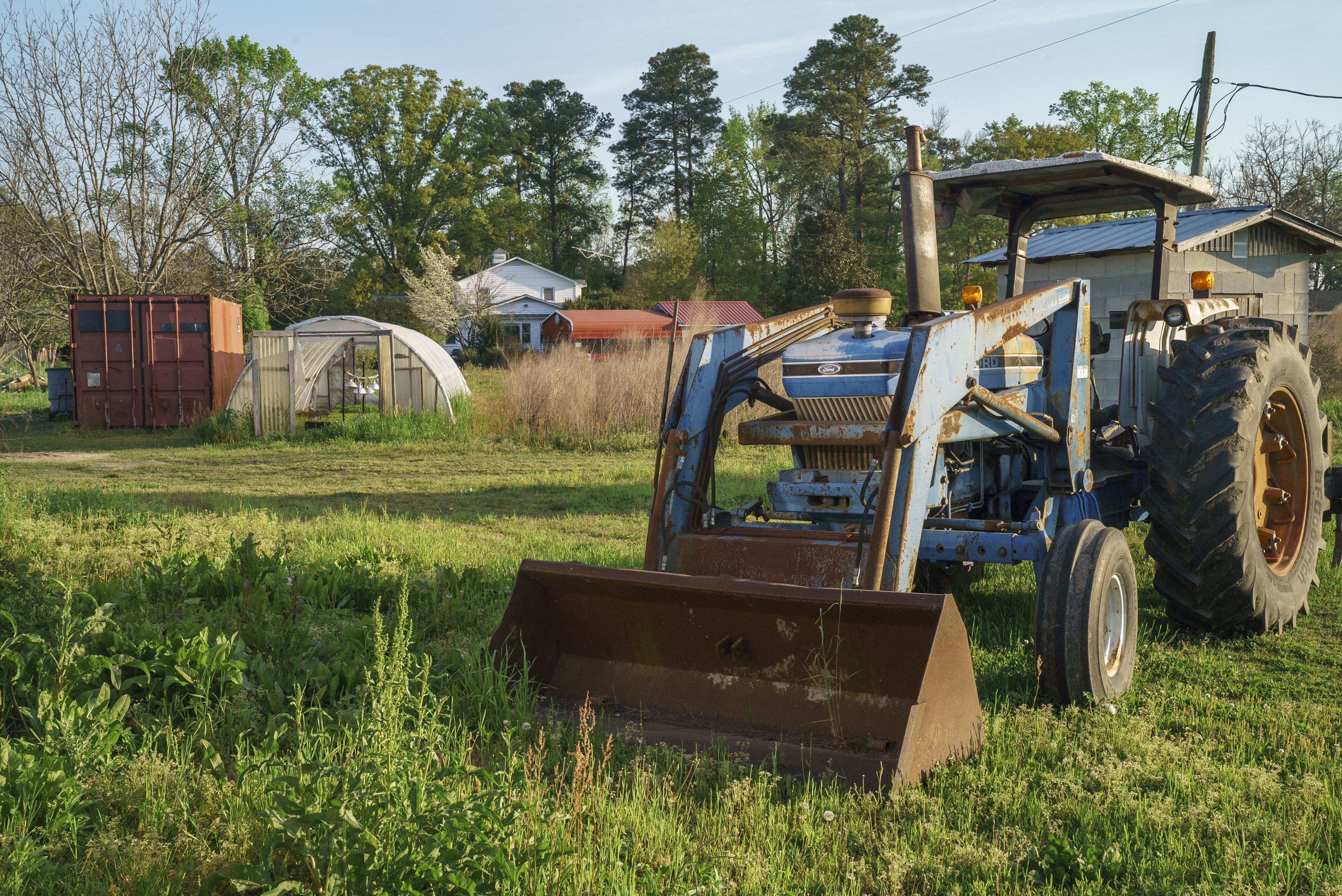 A tractor in a green agricultural field, representing real-world farm research partnerships supporting the UNCP agriculture program.