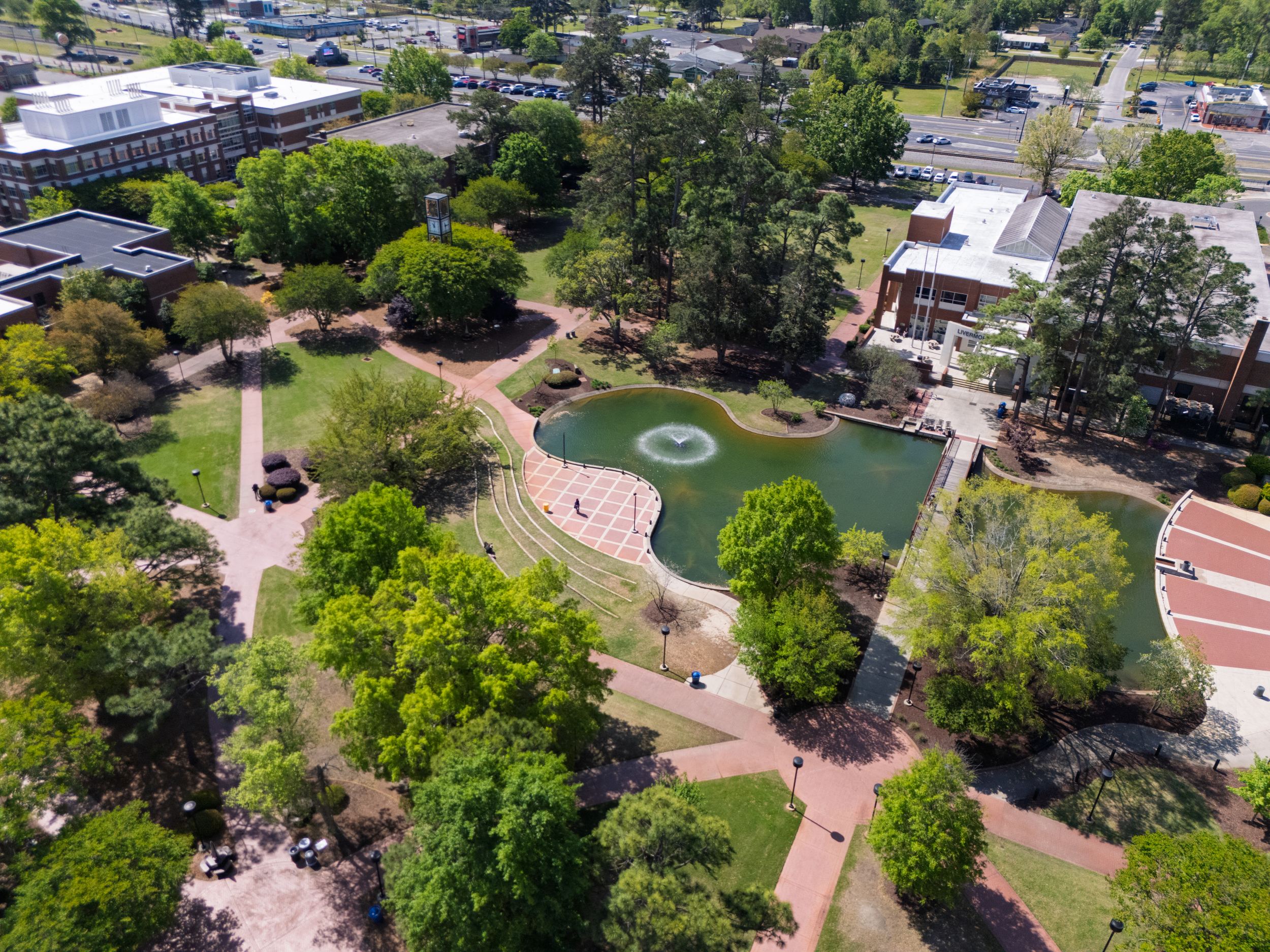 Drone image of the quad, an outdoor area with a water feature, amphitheater and clock towerat UNC Pembroke.