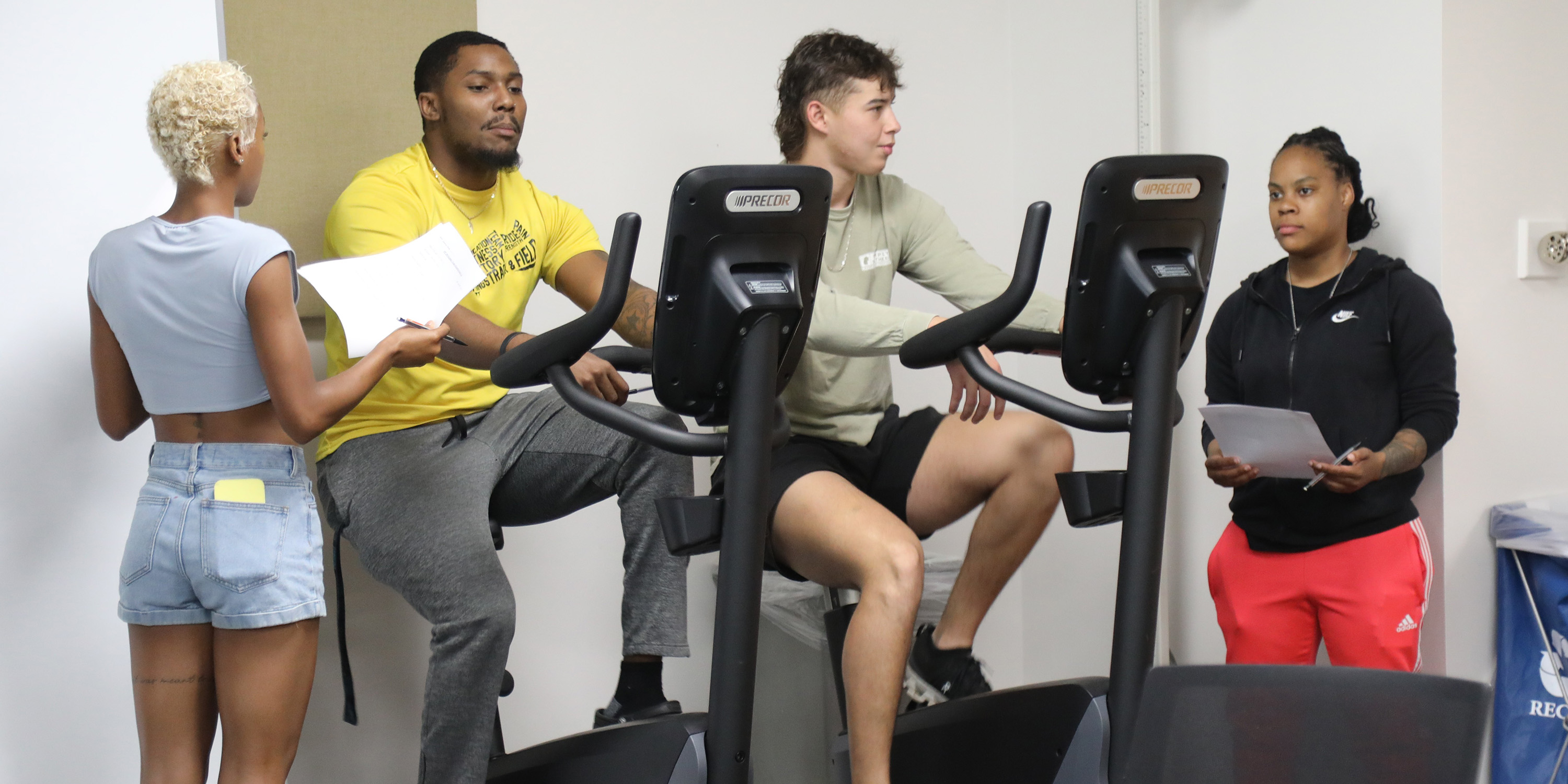 Two kinesiology students evaluating two other students who are on exercise bicycles at UNC Pembroke