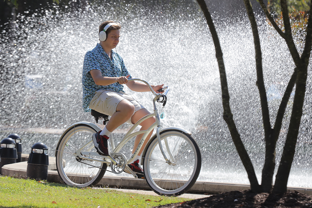 UNCP male student on bike by water feature