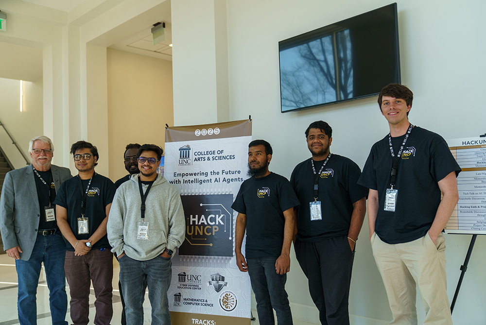 group of students and faculty stand with Hack UNCP sign