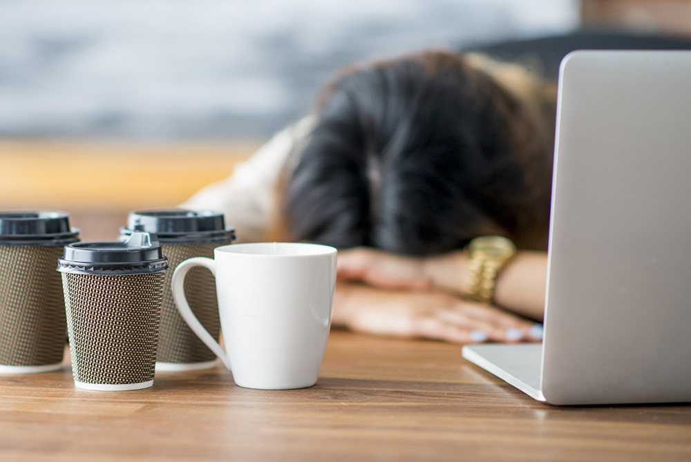 woman falling asleep at computer with coffee
