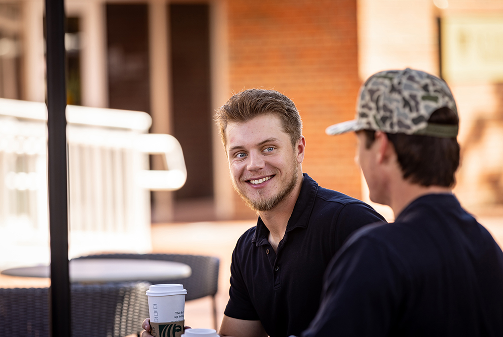 two males sitting at table with coffee UNC Pembroke