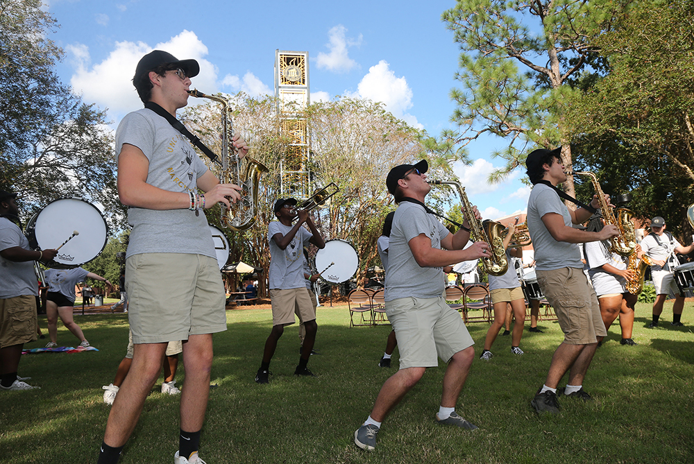 members of UNCP marching band playing instruments with the clocktower in the background