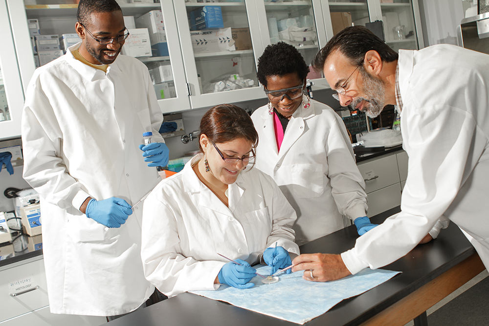 faculty wearing googles and working on an experiment in a science lab