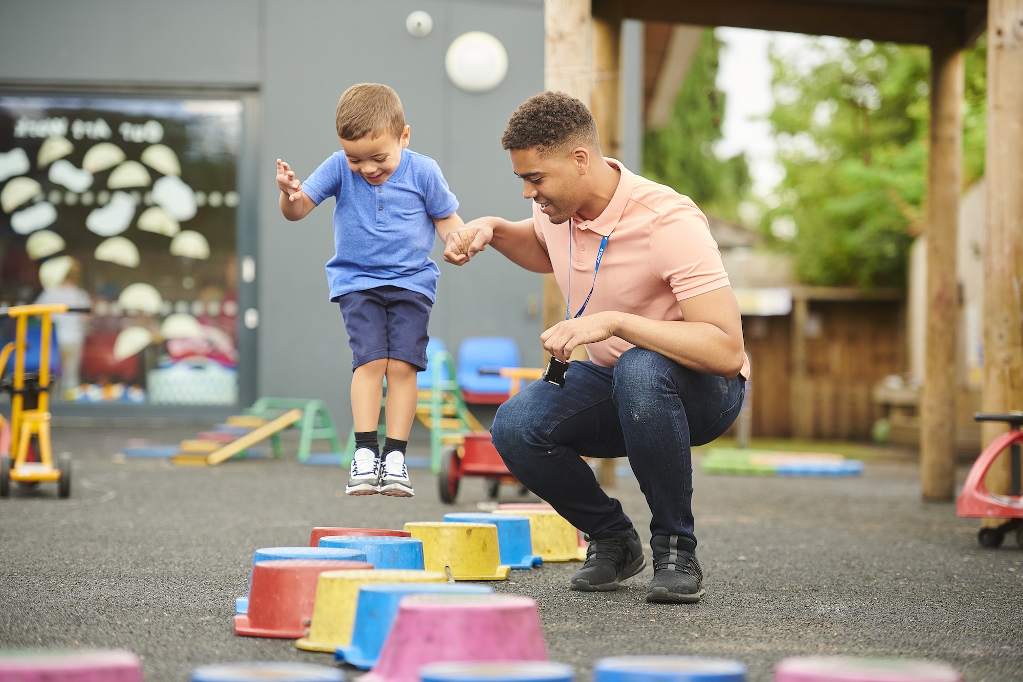 male teacher helping young student jumping cones