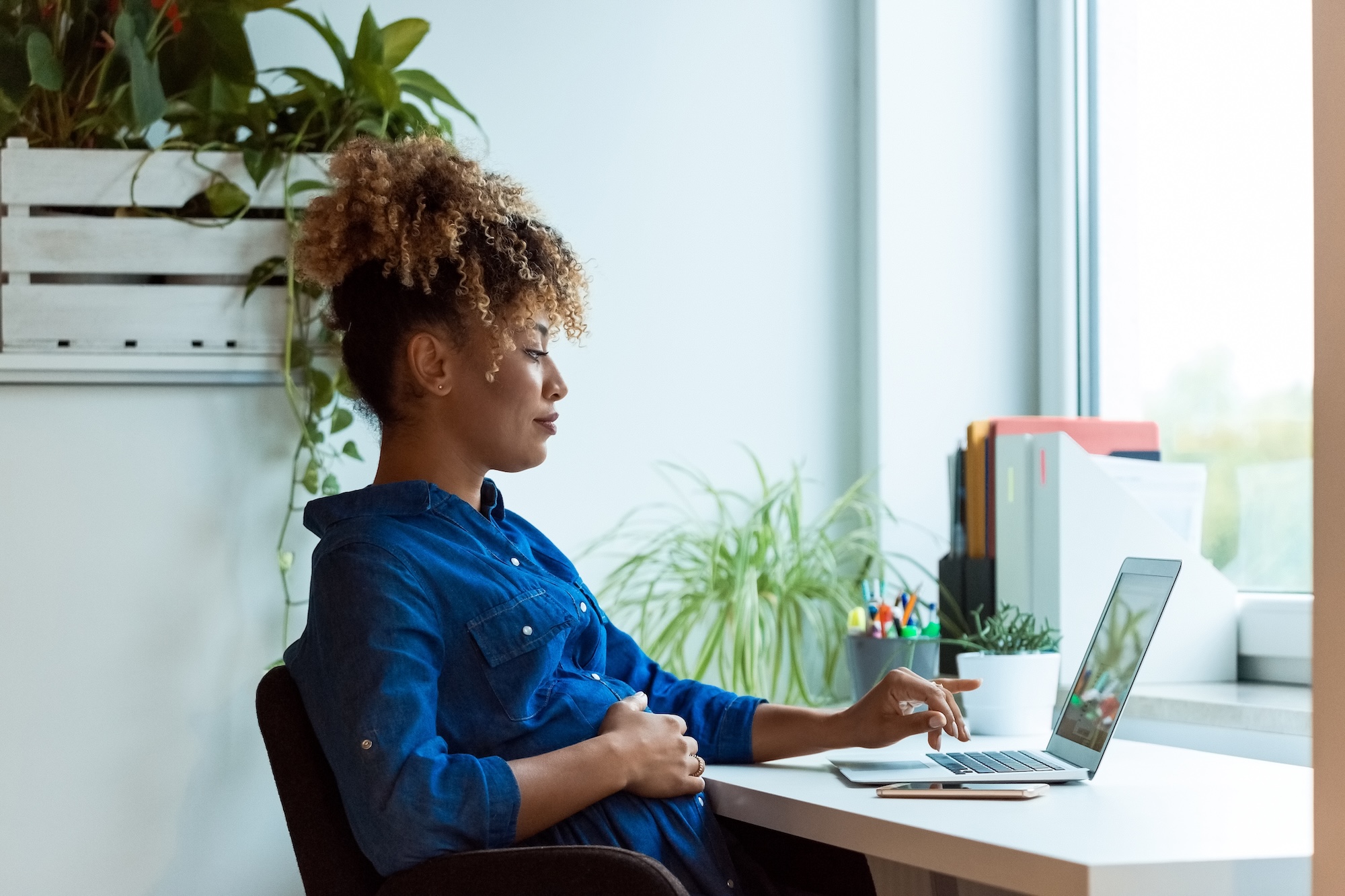 Pregnant woman on a computer with her hand on her belly