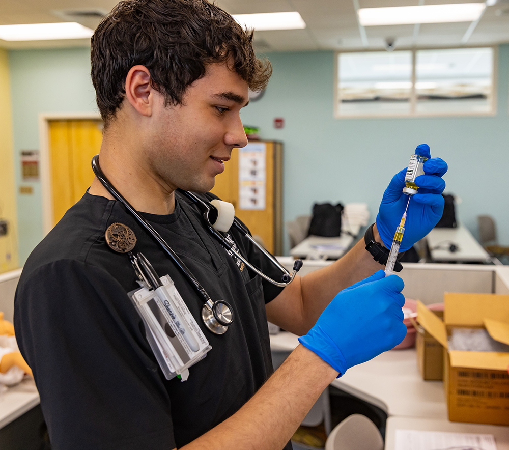 Nursing student filling needle from bottle of medicine