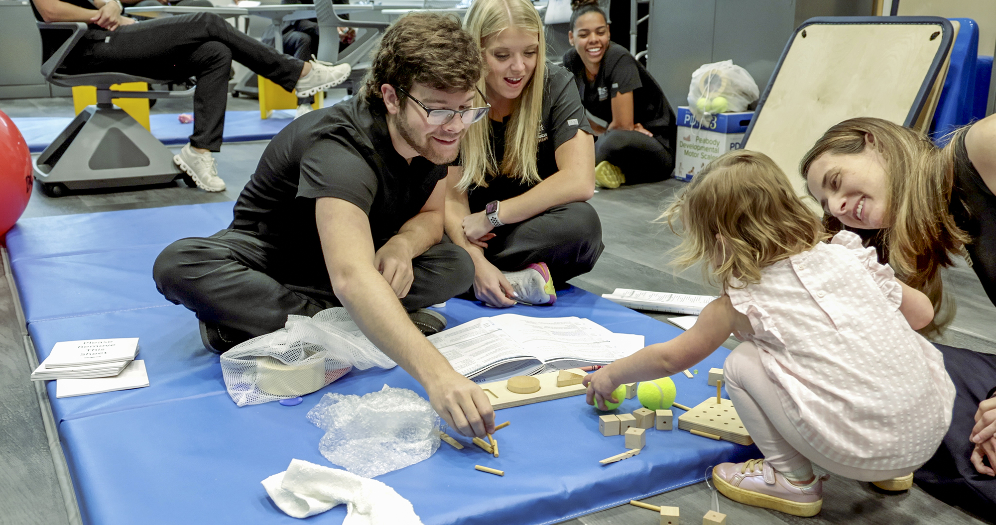 students sit with child on floor in an occupational therapy classroom at UNC Pembroke