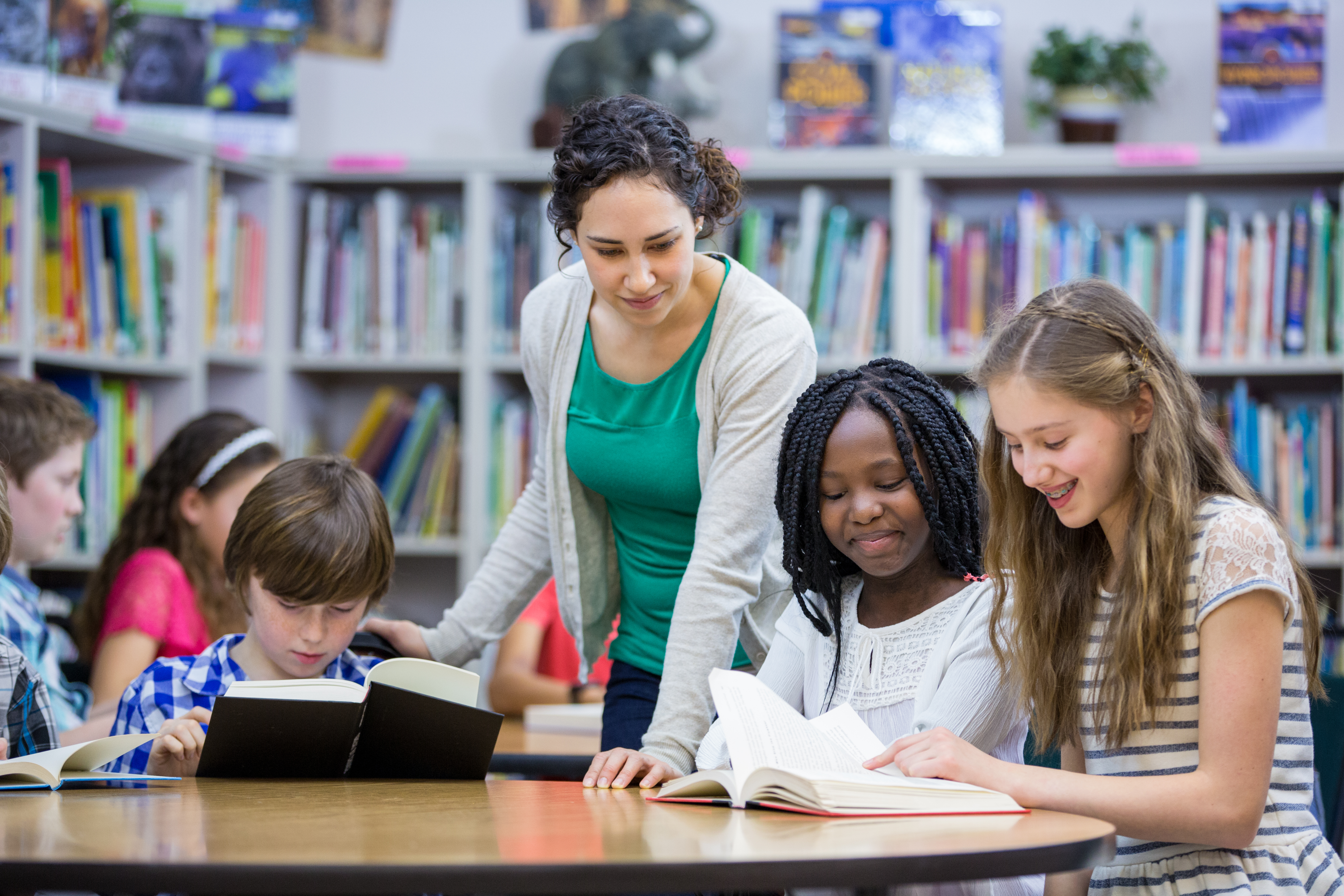 A teacher helping students read in a library