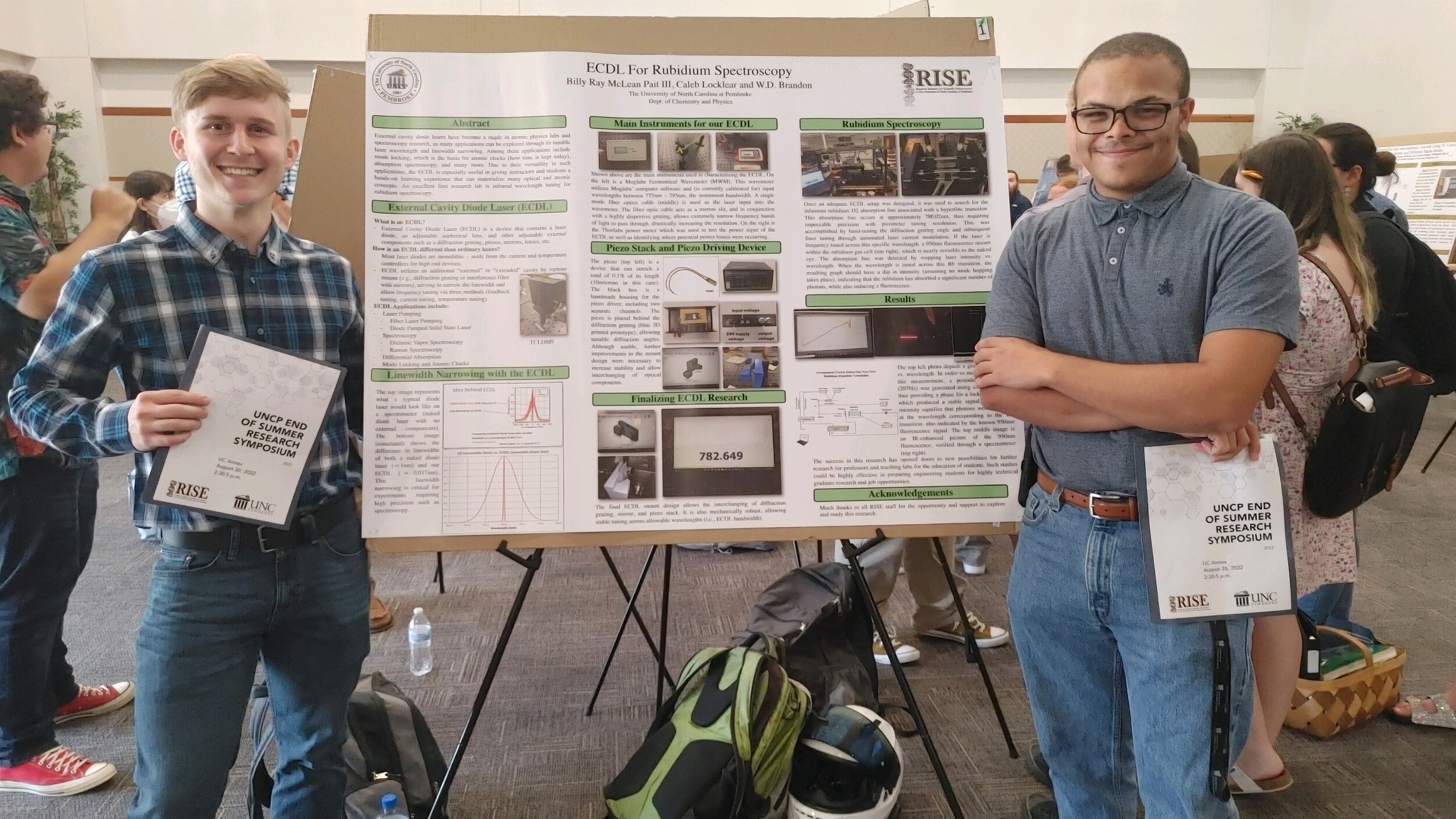 Caleb Locklear (right) stands with a research poster he presented as part of the 3+2 program
