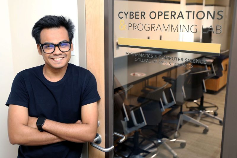Shirsendu Mondal, a cyber security student, posing in front of UNCP's Cyber Operations Programming Lab