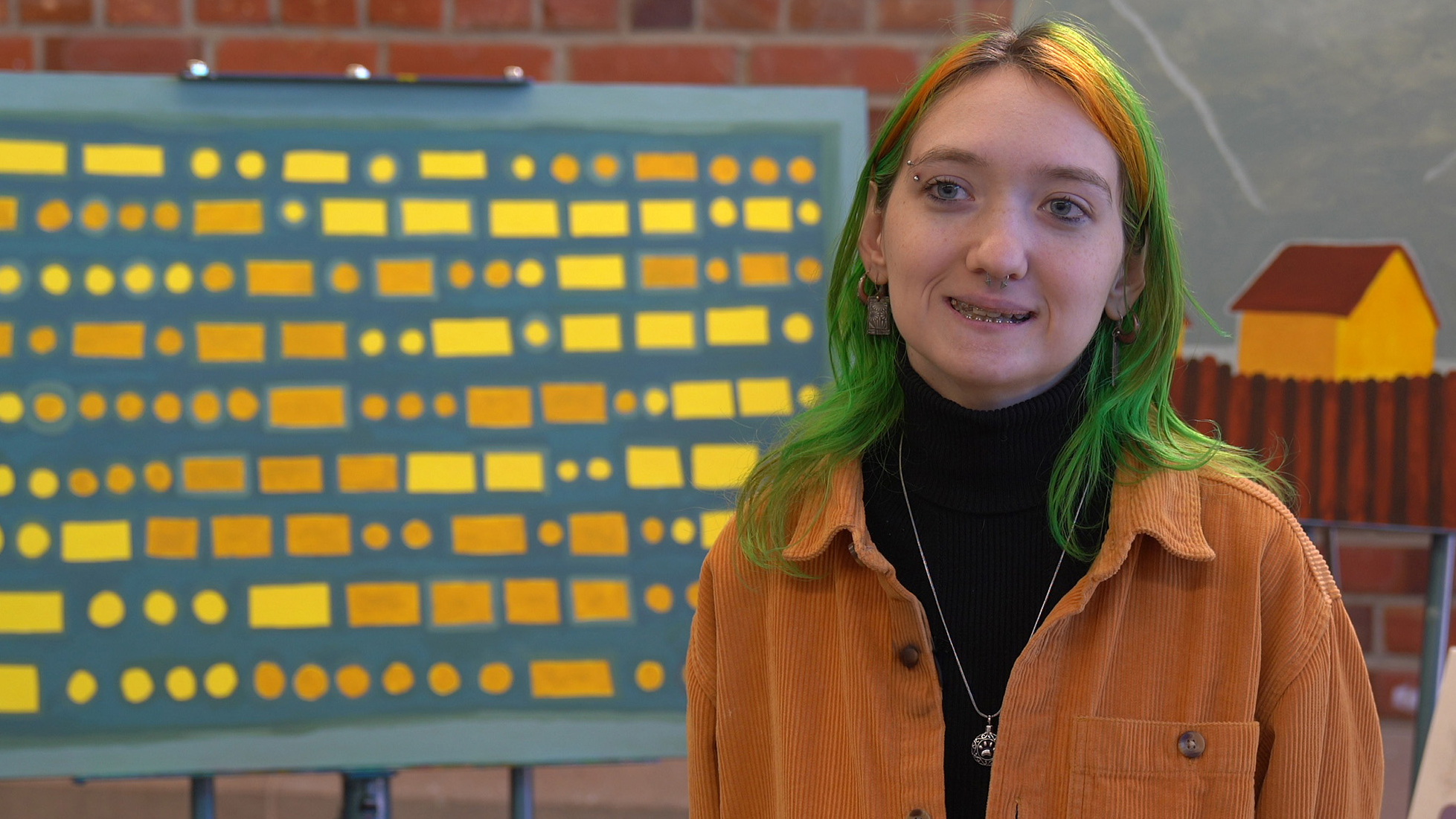 Art student, Bethani Paul, standing in front of her paintings of Morse Code for an interview about UNCP's undergraduate research symposium.