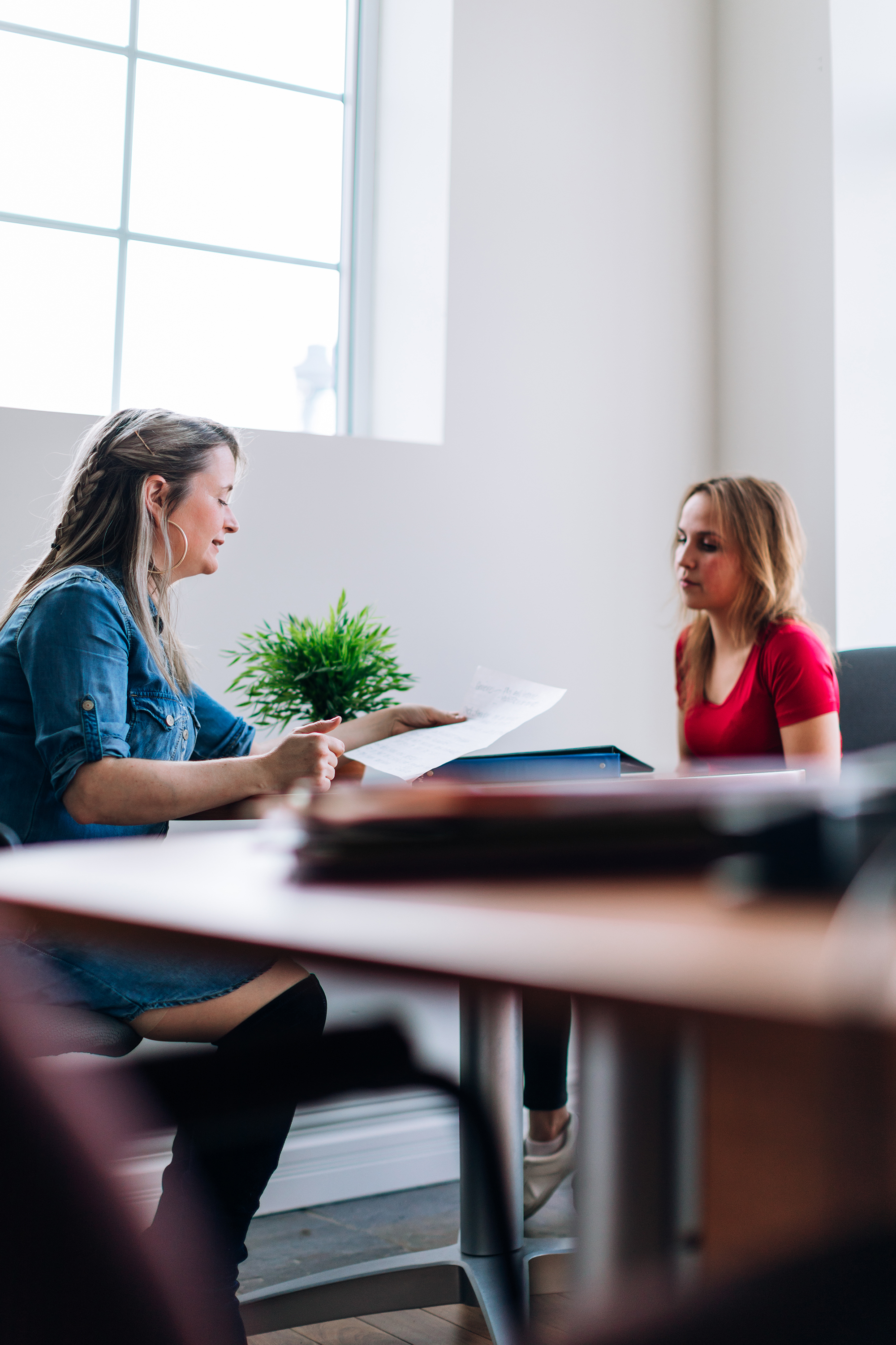 two women sitting at a table talking about papers, one is a social worker