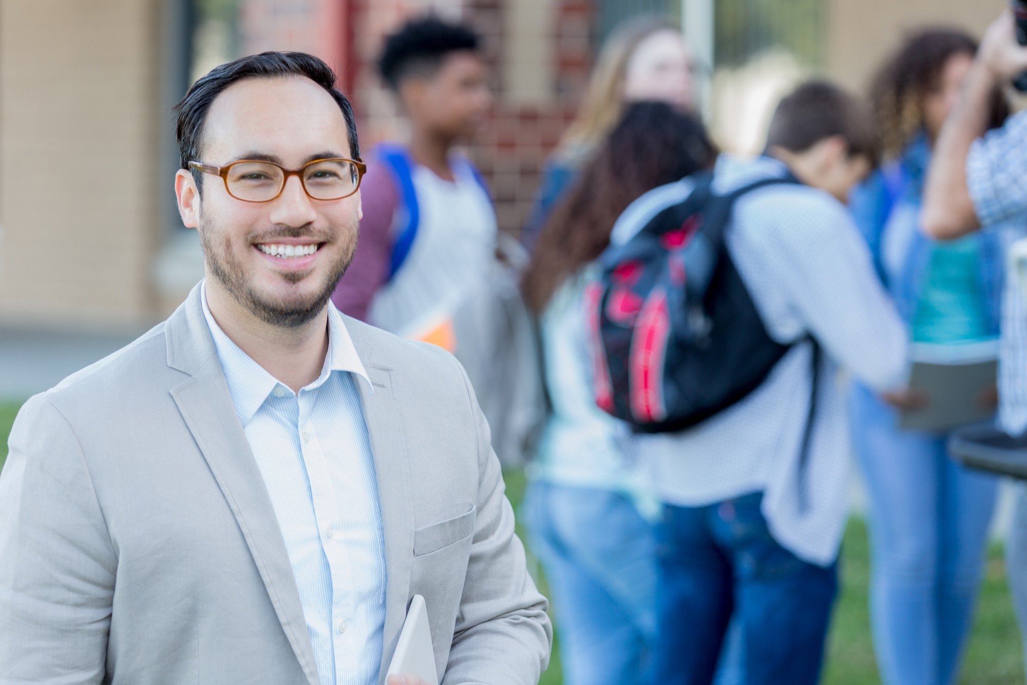 principal outside with kids behind him