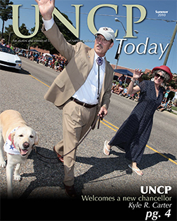 new chancellor kyle r. carter, his wife and dog on the parade route from the cover of the UNCP Today summer 2010 edition
