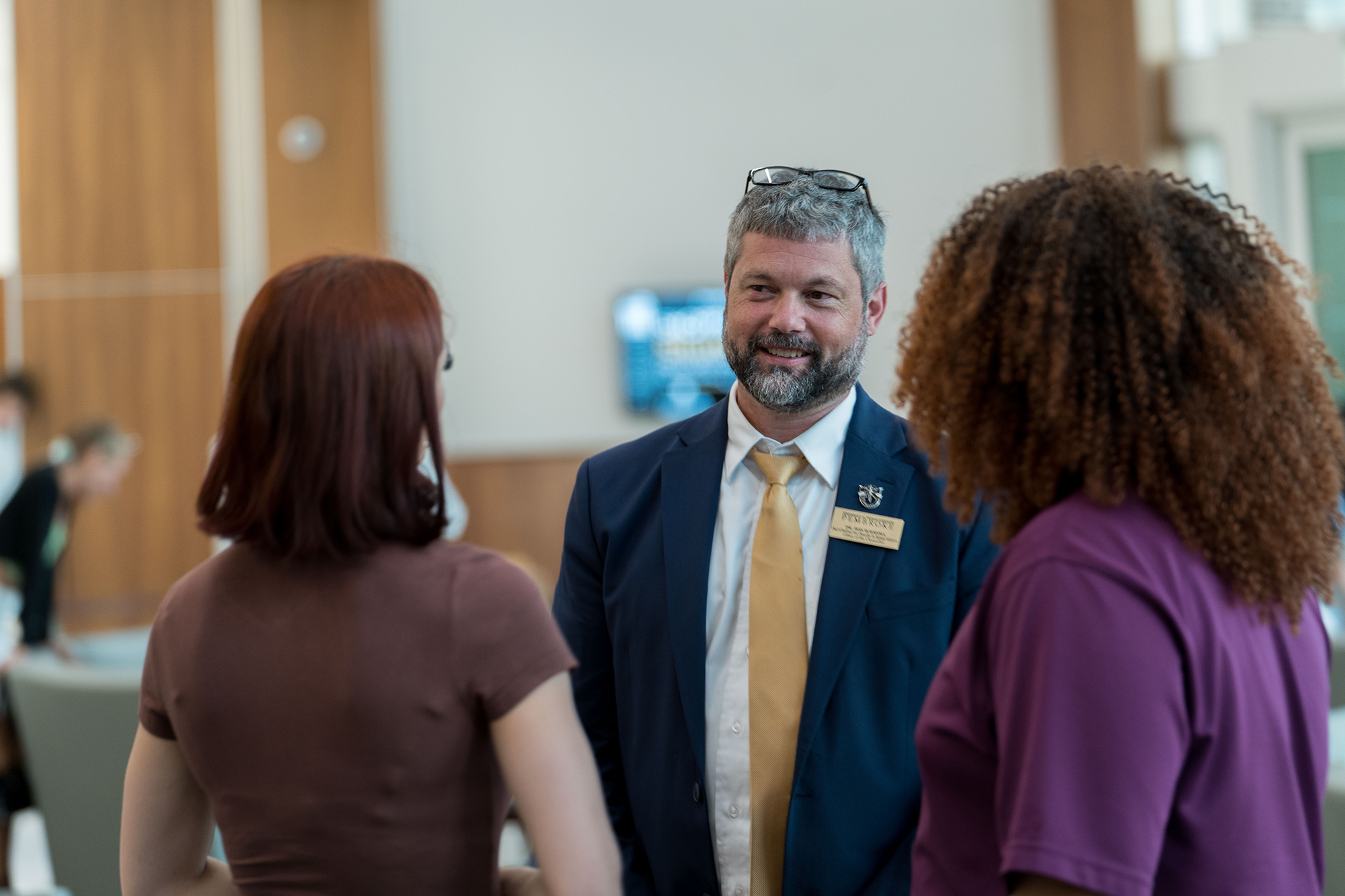 A UNCP Board of Trustees member converses with a Chancellor's Ambassador student on campus.