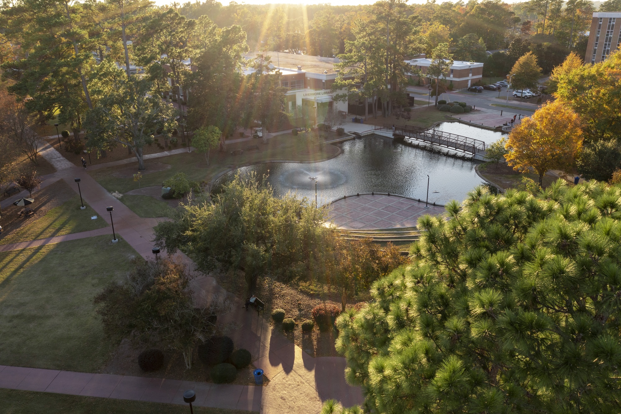 An aerial view of the UNCP campus quad water feature surrounded by trees displaying fall foliage.