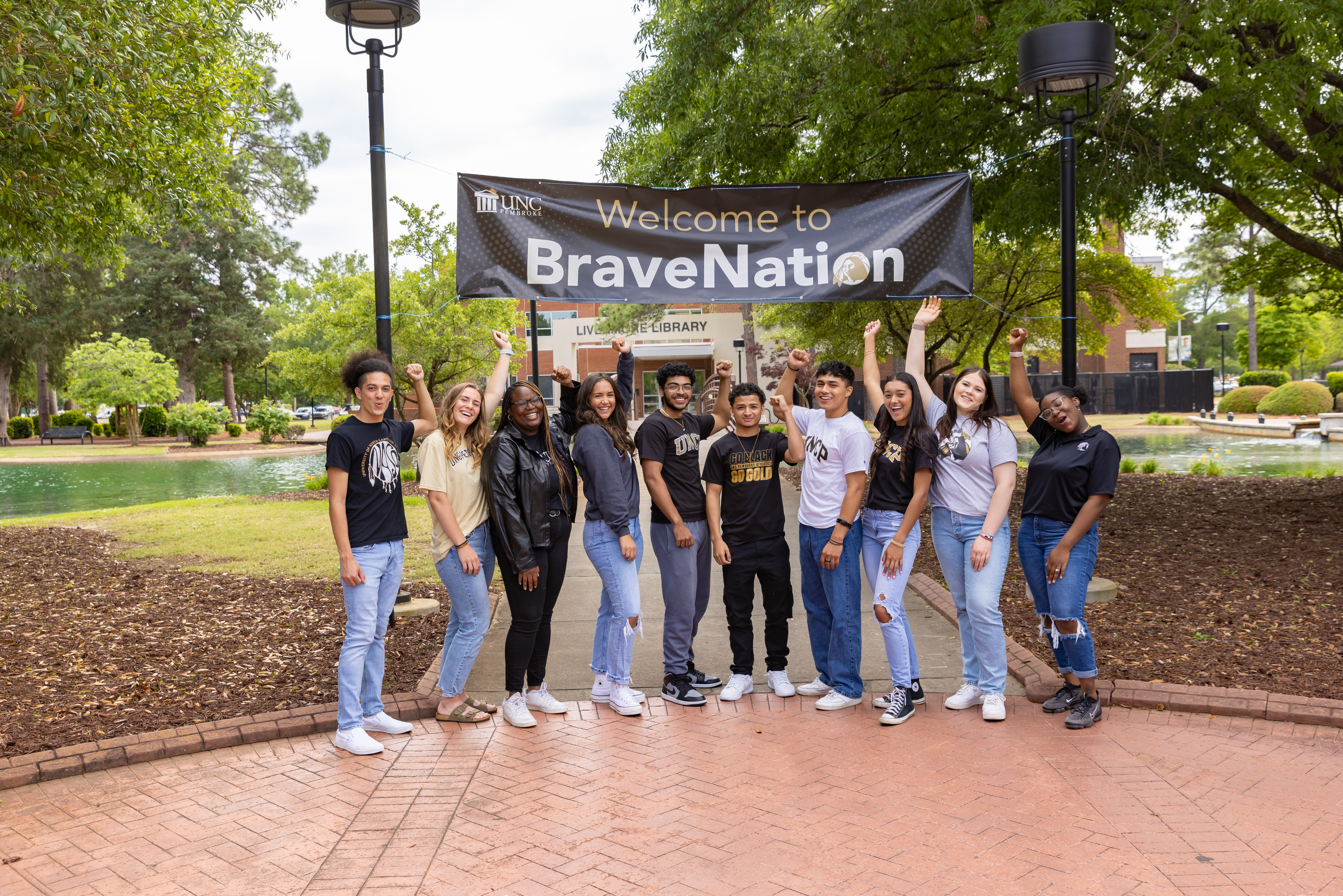 UNCP students celebrating on campus under a Welcome to BraveNation banner