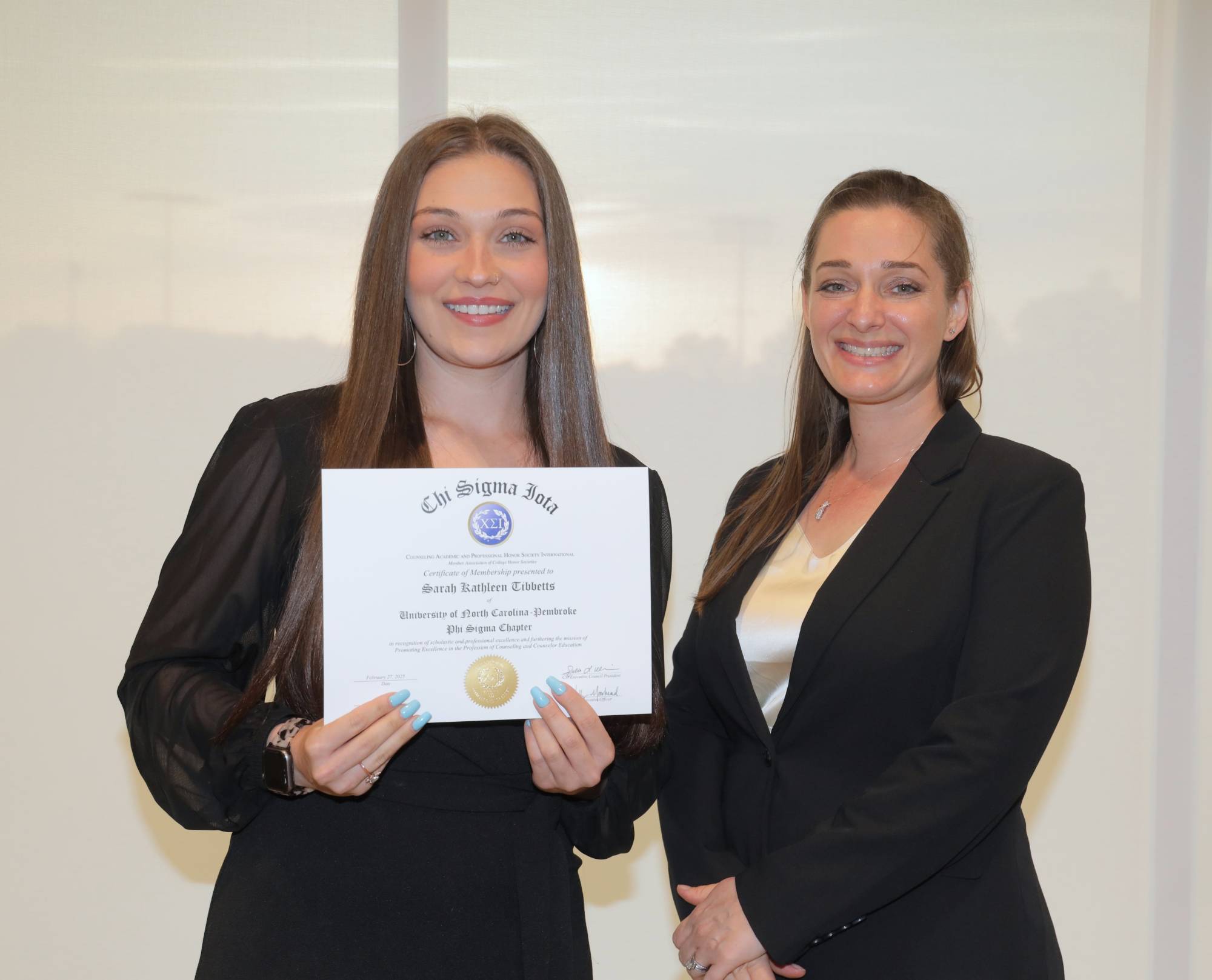 Sarah Tibbetts (left) receives her certificate of induction to Chi Sigma Iota from Dr. Nicole Stargell (right).