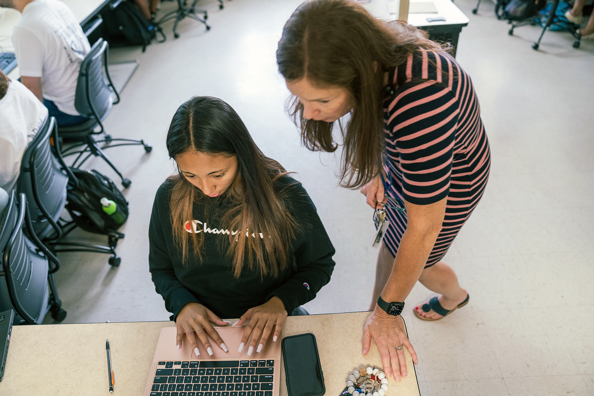 Smiling student engages in a classroom discussion with a professor at the front of the room, learning in a UNC Pembroke English class.