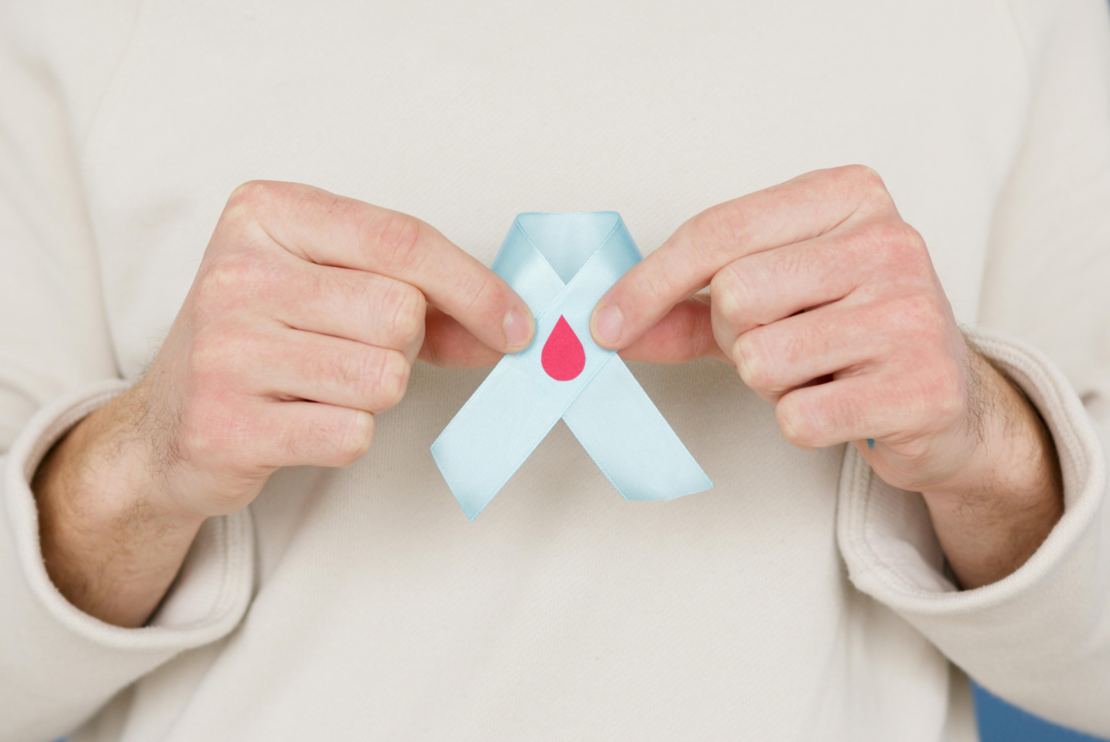 Graphic of someone holding a blue ribbon with a red dot on it.