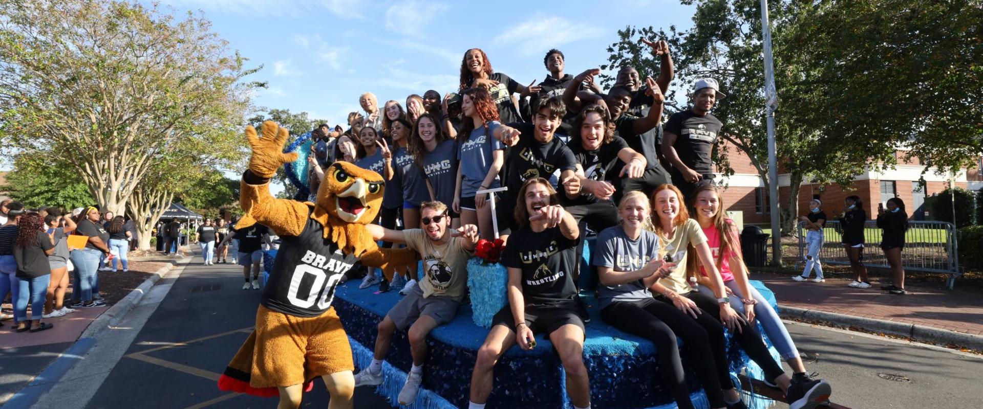 BraveHawk stands with a homecoming float full of UNCP students.