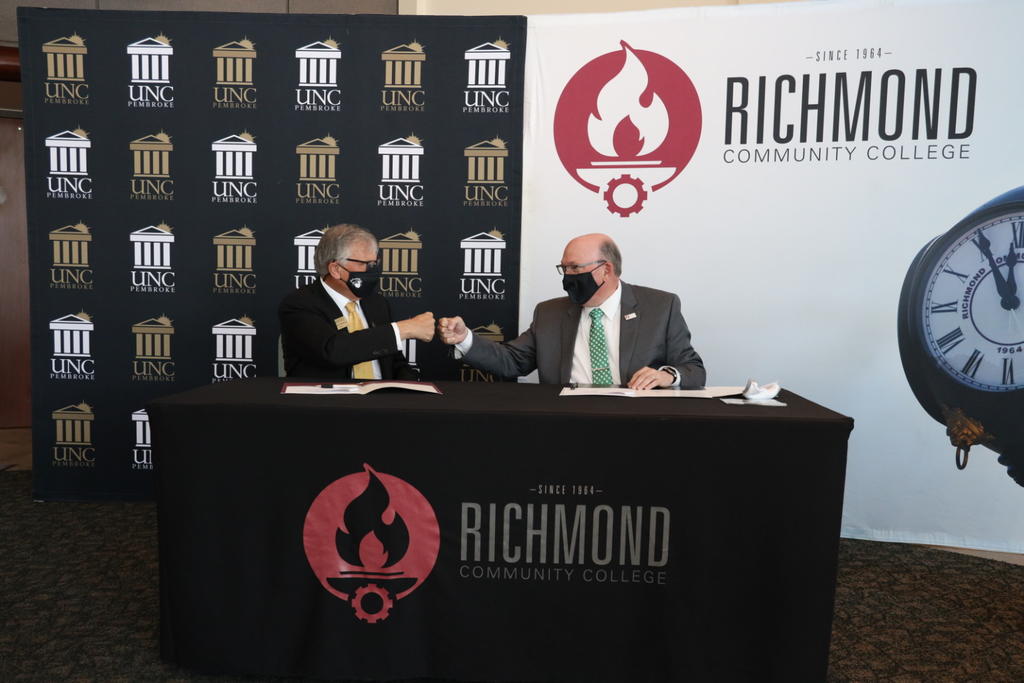 UNCP Chancellor Robin Gary Cummings, left, and RCC President Dale McInnis sign a Growing Your Own partnership