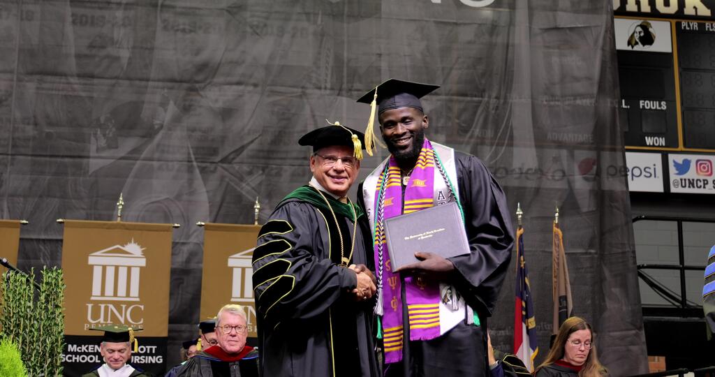 Trent Brown accepts his diploma from Chancellor Robin Gary Cummings