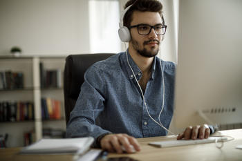 Man at computer with headphones.