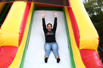 Student sliding down an inflatable with their hands in their air